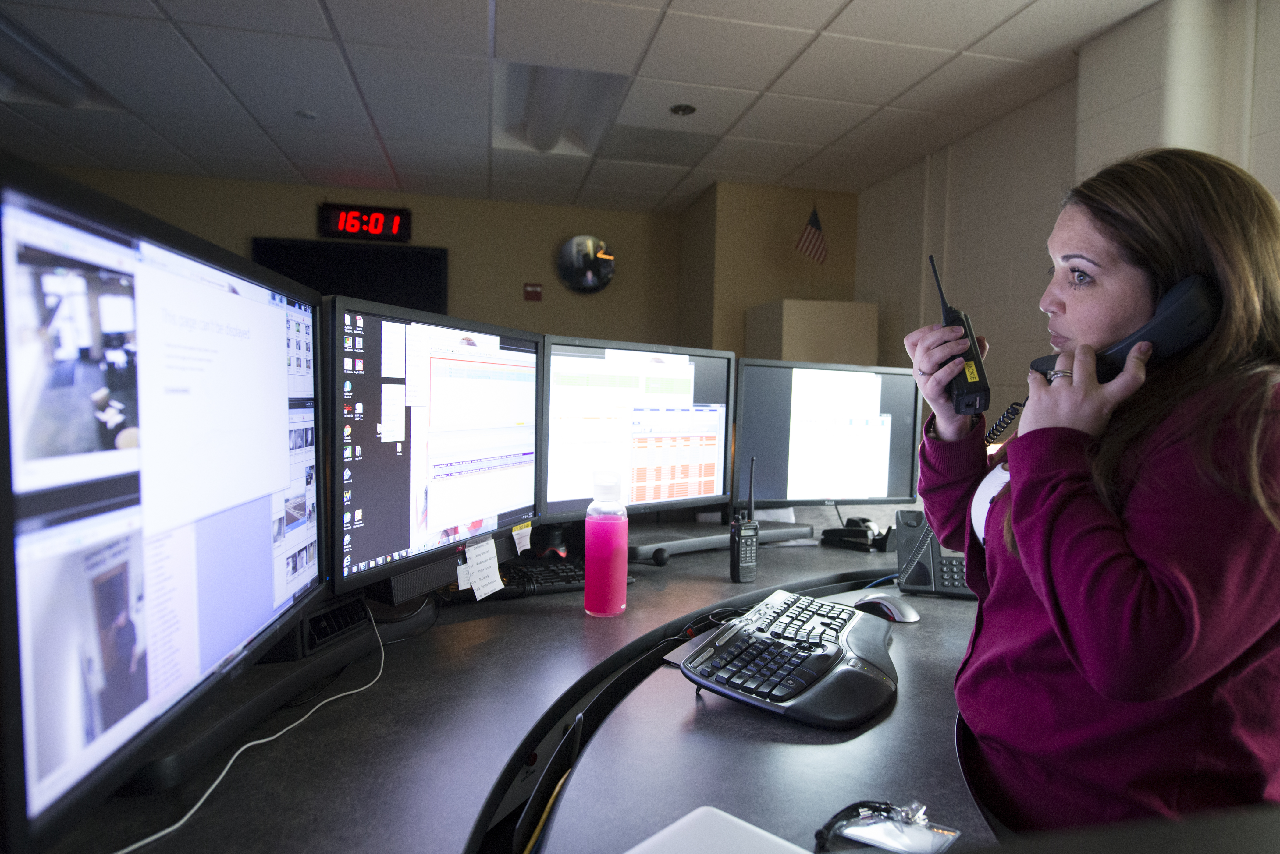 Employee communicating on walkie talkie after viewing surveillance monitors