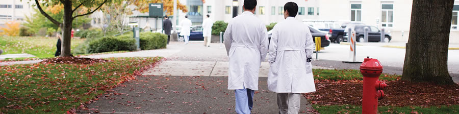 Two faculty members walk across the OHSU campuss during fall.