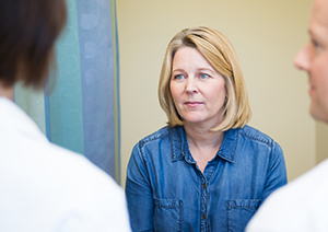 Two doctors talking with a patient during a clinic visit.