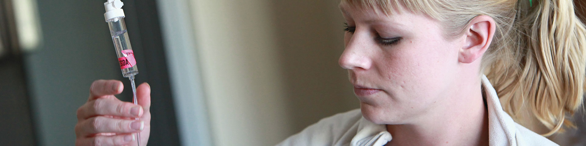 A physician associate checks fluids on a patient IV drip.