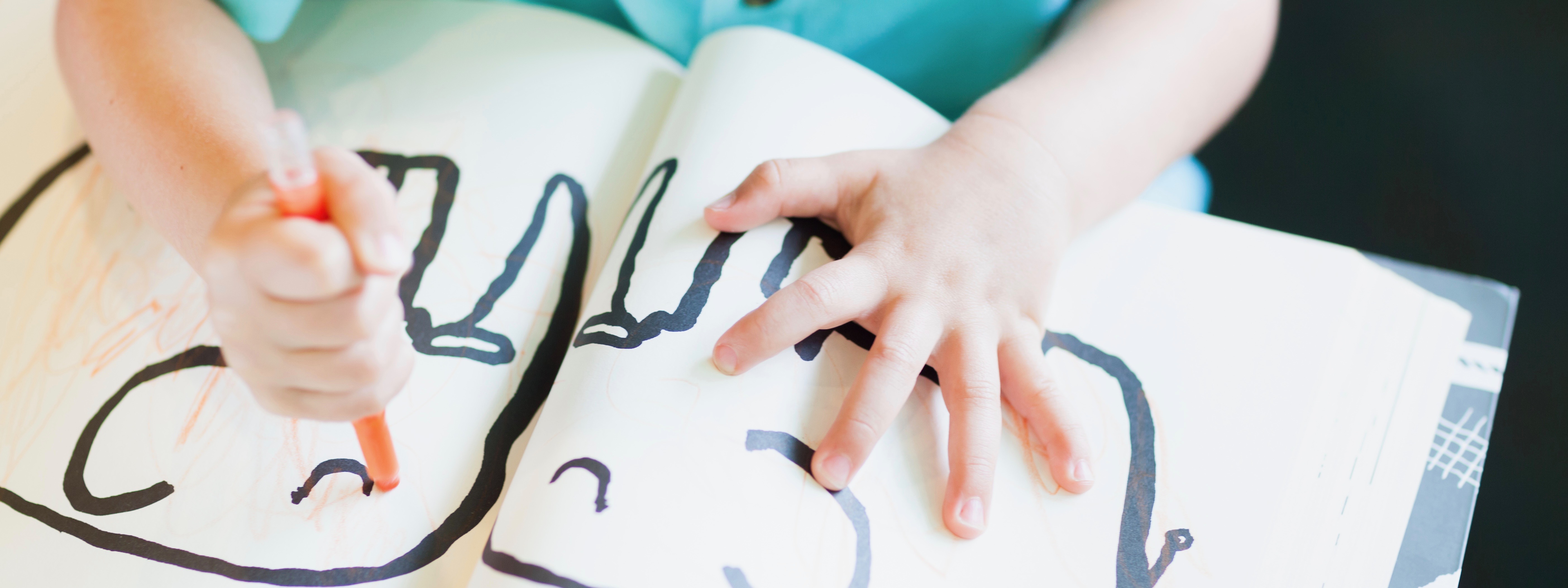 A child coloring a picture of two elephants with an orange marker