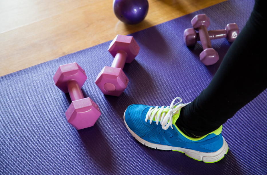 women's foot in blue sneaker next to hand weights