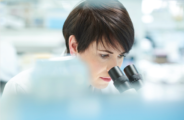 Woman looks through microscope