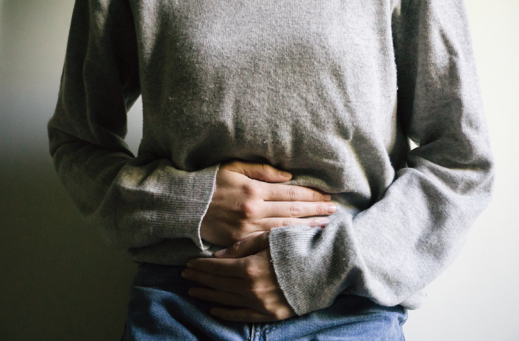 Woman stands with hands on stomach