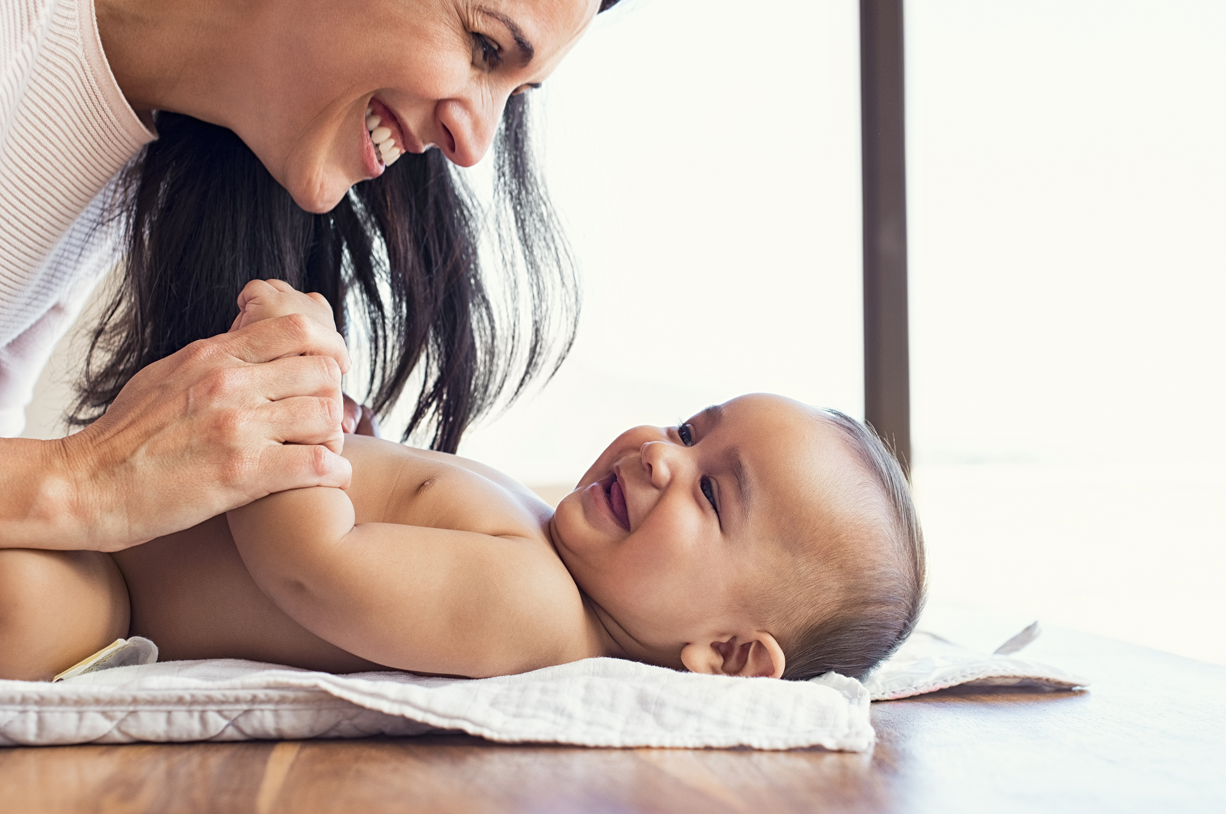 A new parent smiles and laughs with her baby