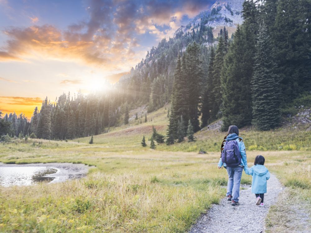 Mother hiking with young daughter on a trail with a view of Mount Ranier.