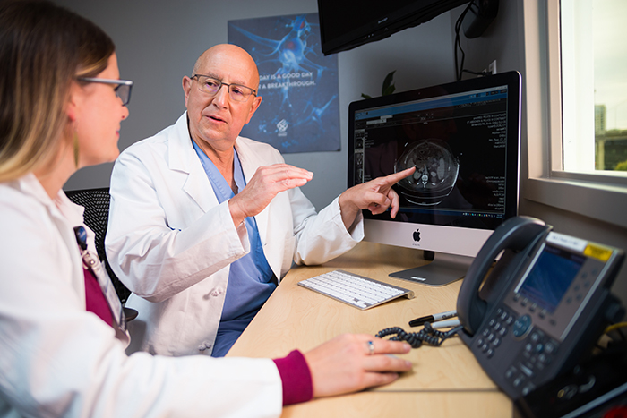 OHSU cancer surgeon Brett Sheppard and nurse practitioner Erica Degenhardt sit together to look at images on a computer monitor.