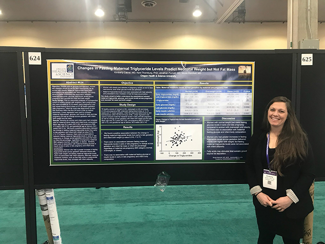 A female resident of OHSU's OB/GYN Residency Program presenting a research poster at a conference.