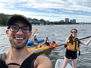 A man taking a selfie while paddle boarding with friends.