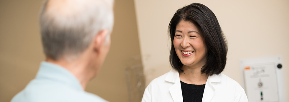 Dr. Jung smiles as she meets with a patient in an OHSU exam room.