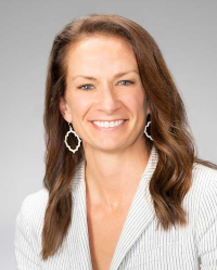 Portrait of Sarah Stahl, brunette smiling at camera, wearing a white blouse and earrings