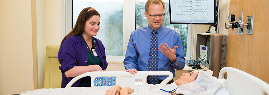 Cecily Key, an EEG technologist, and Dr. David Spencer talking with a patient in a hospital bed