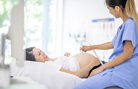 A pregnant woman looks up at the sonographer during an ultrasound.