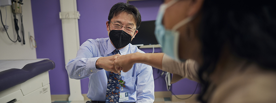 Dr. Otaki smiles as he bumps fists with a patient.