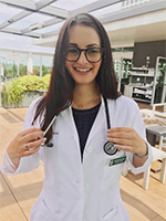 A woman smiling wearing a white coat with a stethoscope around her neck.