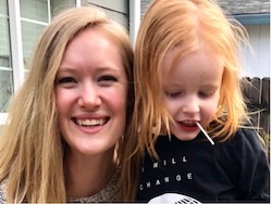 Hannah Sanford-Keller, an OHSU speech-language pathologist, smiles as she holds a patient, Hawk Lamb. He is looking down and sucking on a lollipop.