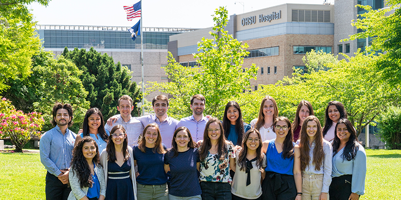 The PGY-1 Pediatric Residency Class standing outside with OHSU Hospital behind them on a sunny day.