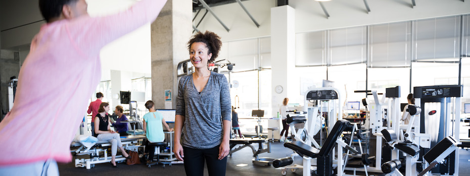 An OHSU physical therapist stands in an OHSU rehabilitation facility while another person does an exercise.