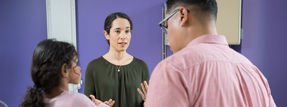 Jenny Wilson, a pediatric neurologist at OHSU, talks with a child and adult in an exam room.