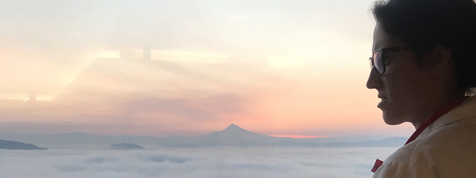 An OB/GYN resident peering out over the sunrise while riding OHSU's aerial tram.