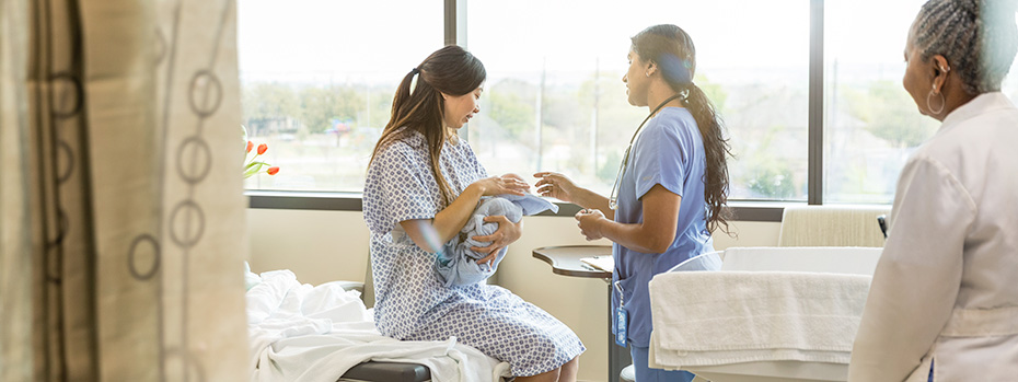 An OHSU nurse-midwifery student provides care to a patient holding a baby, with another health care provider nearby.