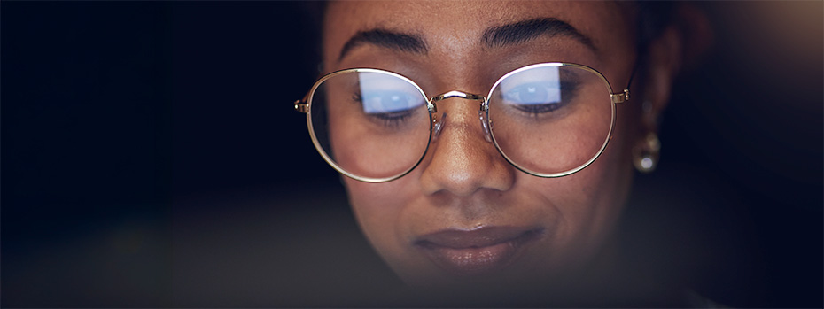 Close-up view of a nursing student wearing round glasses, looking down while studying.