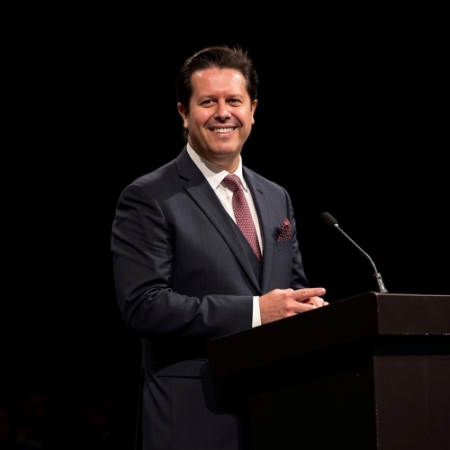 Photo of Dr. Andre Romano smiling in front of a podium