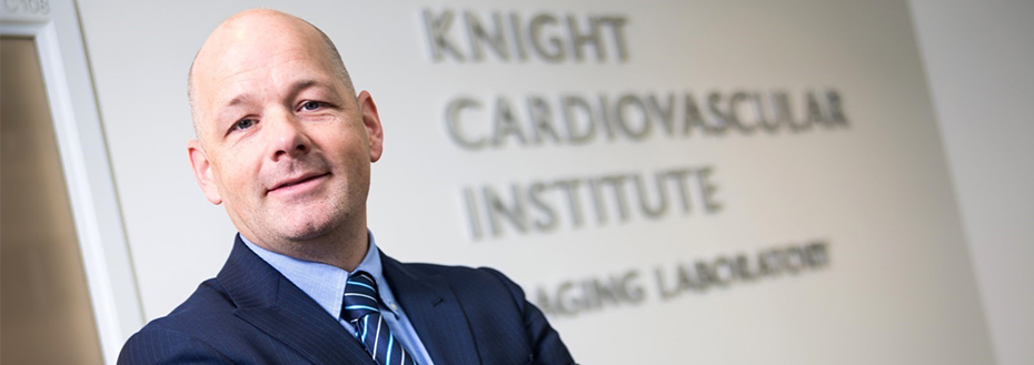 A portrait of Dr. Broberg in front of the Knight Cardiovascular Institute Imaging Laboratory.