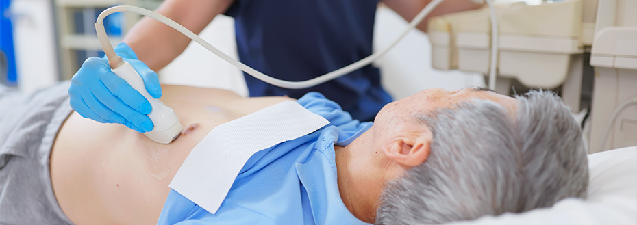 A doctor places an echocardiogram probe on the chest of a male patient.