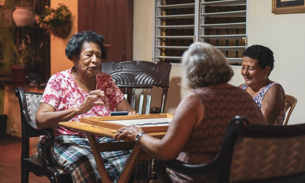A group of three women gather around a table.