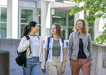 Three students walk outside on the OHSU campus on a sunny day.