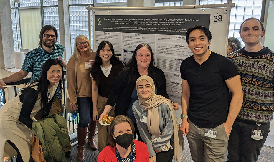 Nine researchers smile in front of a research presentation poster.