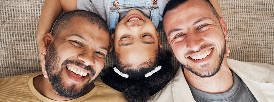 Two men and a child posing for a photo while laying on the floor