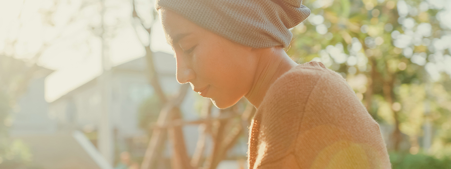 A woman looking down while outside in the sunshine during magic hour.