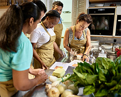 Students in a kitchen classroom work together on a hands-on nutrition lesson, preparing ingredients and following a recipe.