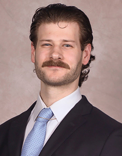 A headshot of neuroscience candidate Evan Multala against a brown marbled wall.