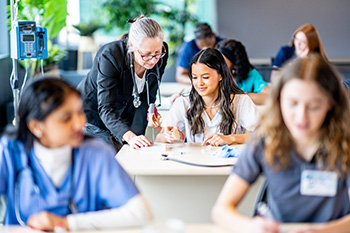 Faculty member teaching student in a health sciences classroom.