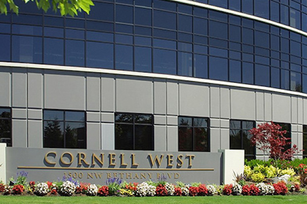 Modern building with Cornell West written on a sign flanked with flowers.