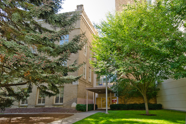 Brick building with awning with trees in the foreground Brick building with awning with trees in the foreground