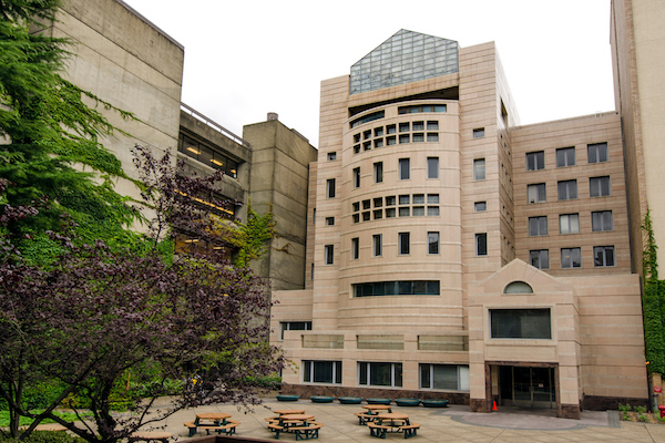Tall brick building with pointed glass top with a square with picnic tables in front Tall brick building with pointed glass top with a square with picnic tables in front